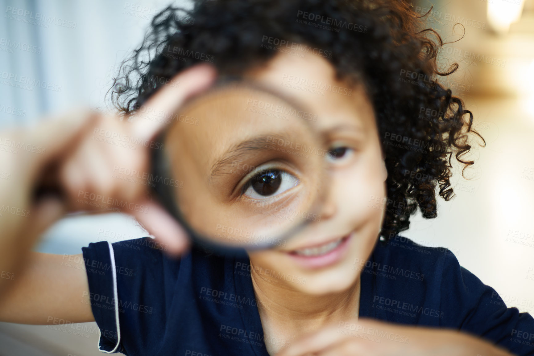 Buy stock photo Shot of a little boy holding a magnifying glass to his eye