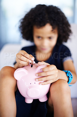 Buy stock photo Shot of a little boy dropping two coins into his piggybank