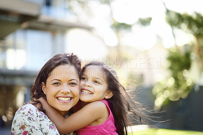 Buy stock photo A cute little girl hugging her mom while they are standing in the garden
