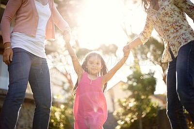 Buy stock photo A cute little girl being swung by her mother and grandmother in the garden