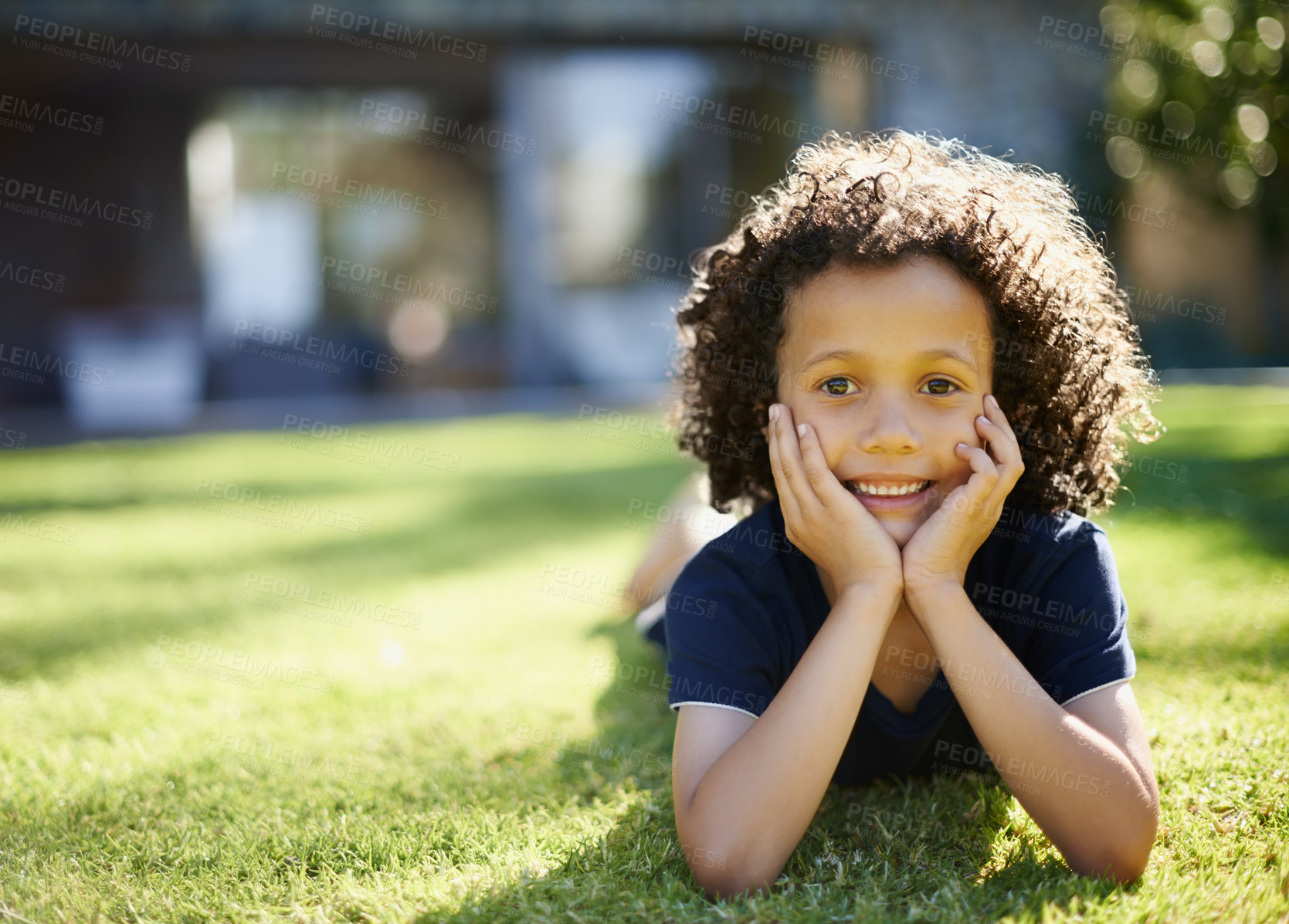 Buy stock photo A cute little boy lying on the grass with his head in his hands