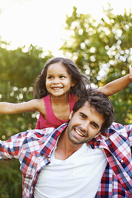 Buy stock photo An attractive young father piggybacking his young daughter with a smile