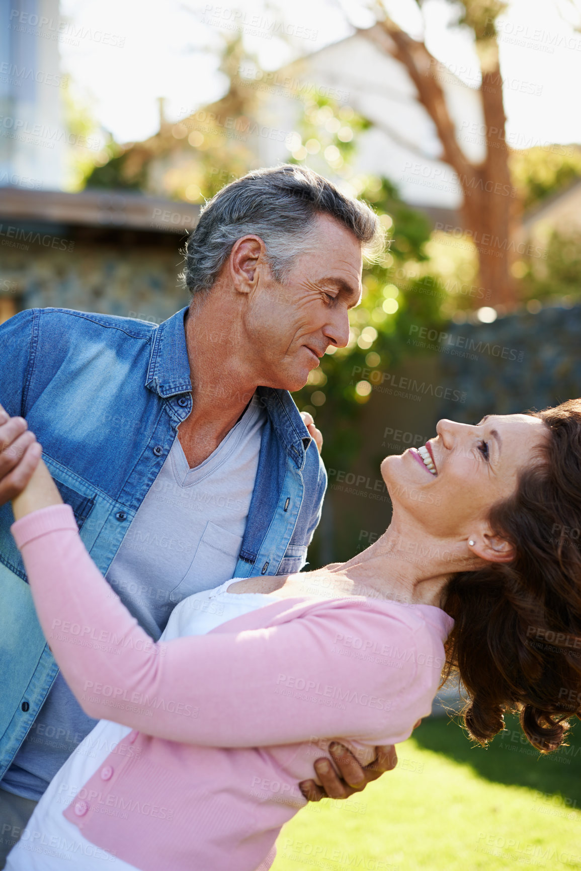 Buy stock photo Mature couple dancing outside in the garden. Senior husband and wife having fun and bonding in a park. Man holding his partner during a dance in nature. Man admiring his wife in their backyard