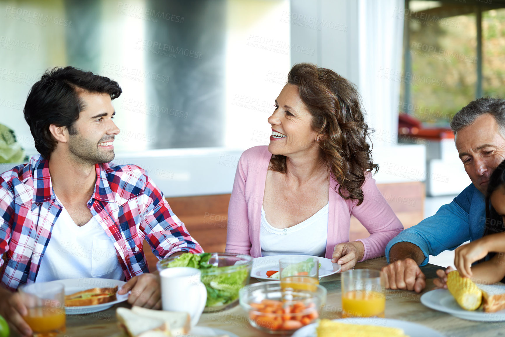 Buy stock photo Happy, family and healthy brunch at table together for wellness, salad and juice for nutrition. Diversity, Man or woman with joy in home or happiness for diet with fresh vegetables, eating with smile
