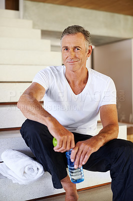Buy stock photo Portrait of one mature fit man eating apple and drinking bottle of water at home for good wellbeing and vitality. Happy healthy guy enjoying balanced nutritious diet and exercise for active lifestyle
