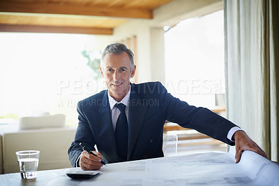 Buy stock photo A professional businessman going over some plans and making calculations 