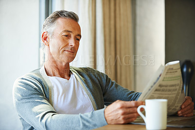 Buy stock photo Mature, man and newspaper for reading in house, relax and information or articles in morning with coffee. News, breakfast table and rest and calm for entertainment pages, current events in apartment