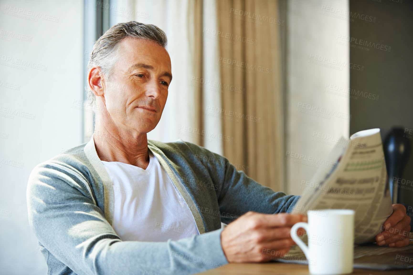 Buy stock photo Mature, man and newspaper for reading in house, relax and information or articles in morning with coffee. News, breakfast table and rest and calm for entertainment pages, current events in apartment