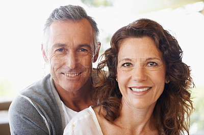 Buy stock photo Portrait of happy faces of a mature loving couple bonding at home. Smiling and affectionate husband and wife hugging while relaxing together. Cheerful man and woman in a loving positive relationship 