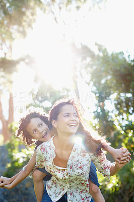 Buy stock photo A young mother piggybacking her son in the park