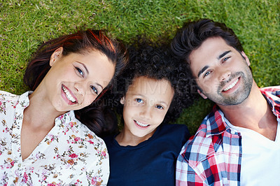 Buy stock photo Top view, sunshine and family on grass, portrait and happiness with smile, bonding together and nature. Face, joyful parents or boy with love, outdoor and son with mother, father or relax with summer
