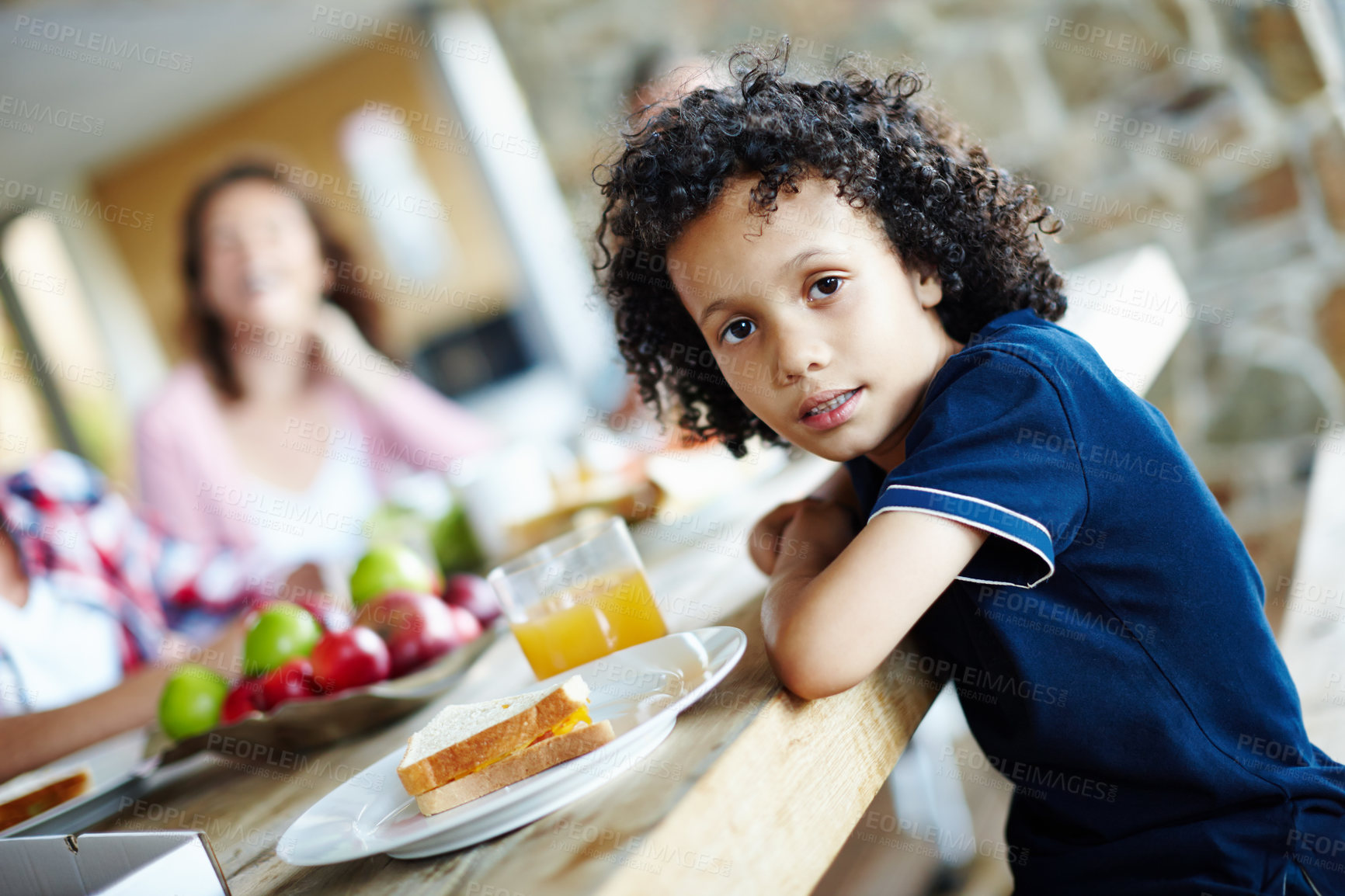 Buy stock photo A cute little boy sitting at the table during a family meal time