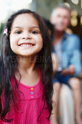 Buy stock photo A cute little girl standing in the foreground with her grandfather in the background