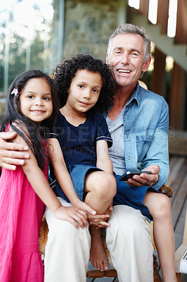 Buy stock photo A smiling grandfather showing his grandchildren his smartphone