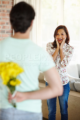 Buy stock photo Couple, house and flowers with woman surprised for anniversary with expression in living room. Marriage, valentines day and relationship with shocked for gift or present with romance in Spain.