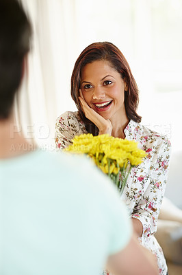 Buy stock photo A delighted young woman receiving flowers from her boyfriend