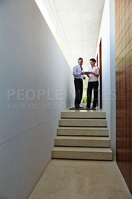 Buy stock photo Two colleagues having a discussion in the hallway