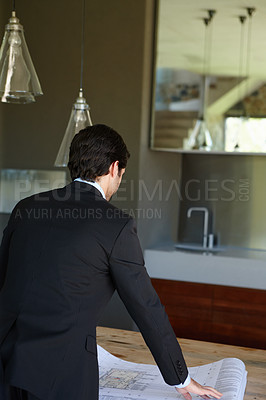 Buy stock photo Rear view image of an architect analysing a house plan