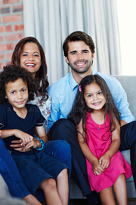 Buy stock photo Portrait image of an adorable family sitting on the sofa in their home