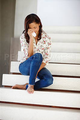 Buy stock photo A young woman sobbing on the staircase