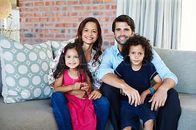 Buy stock photo A young family sitting on the couch together in their living room