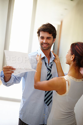 Buy stock photo Handsome man reading while his wife dresses him