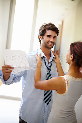 Buy stock photo Handsome man reading while his wife dresses him