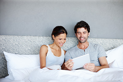 Buy stock photo Happy couple, watching and bed with tablet for online streaming, subscription or connectivity at home. Man and woman with smile in relax on technology for show, movie or browsing in bedroom at house