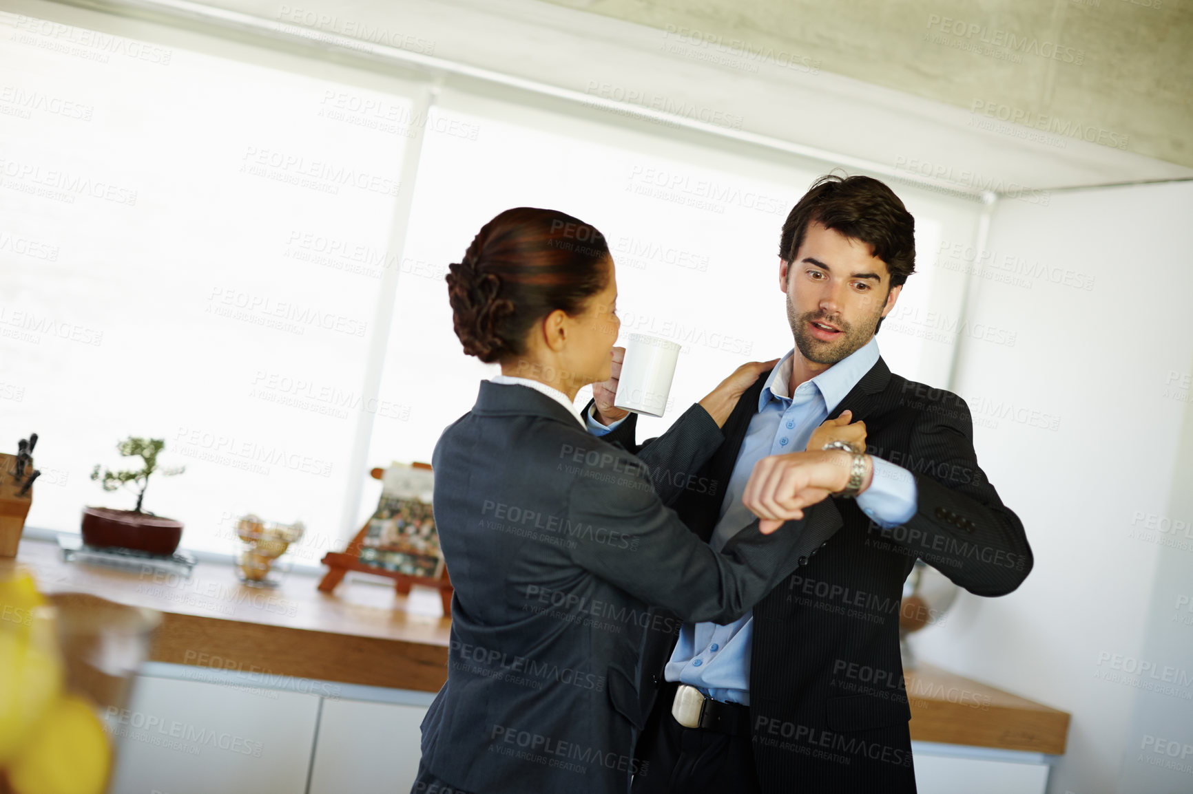 Buy stock photo Attractive woman fixes her husbands collar while he expresses surprise looking at his watch