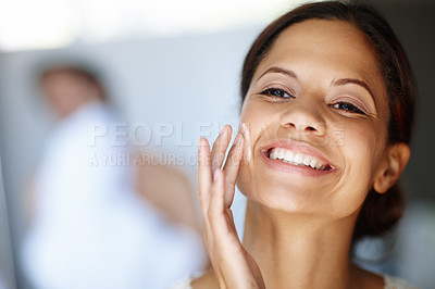 Buy stock photo An attractive young woman taking care of her skin in the morning with a smile