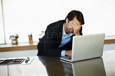Buy stock photo Anxious young businessman working on his laptop at home