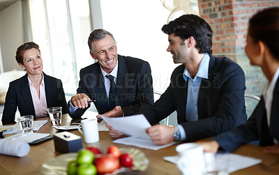 Buy stock photo A team of positive suit-clad businesspeople having a boardroom meeting together