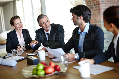 Buy stock photo A team of suit-clad businesspeople having a boardroom meeting together