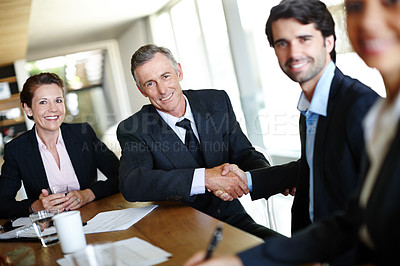 Buy stock photo A group of professional businesspeople in a meeting and concluding a deal with a handshake
