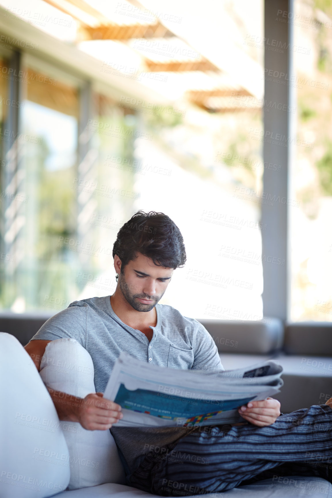 Buy stock photo Shot of a man reading his newspaper in his living room