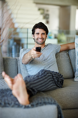 Buy stock photo Home, portrait and man with remote on sofa for streaming game, football and rugby for entertainment. House, living room and happy guy on couch for watching tv, changing channel and relax in lounge