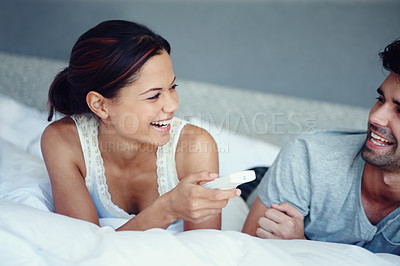 Buy stock photo Shot of a happy couple lying on their bed watching television together