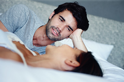 Buy stock photo Shot of a smiling couple lying in bed and talking