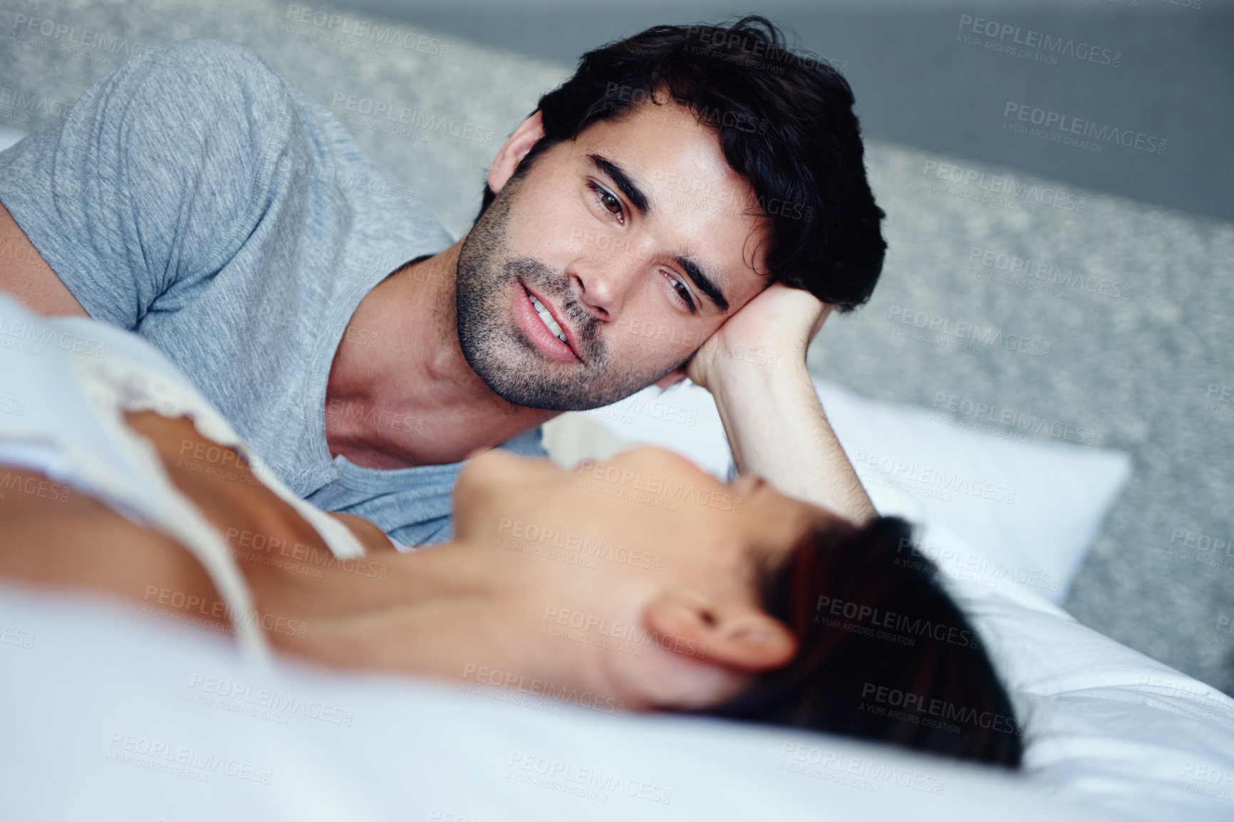 Buy stock photo Couple, happy and lying in bed together talking with love for communication, romance or relationship. Smiling, man and woman cuddle in home for morning conversation, discussion and intimate moment