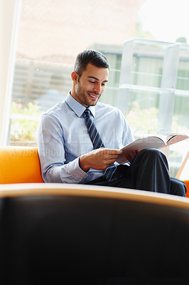 Buy stock photo Office, businessman smile and reading magazine or catalog with waiting for appointment and work break. Corporate, book and happy lawyer guy on sofa with law journal for information and knowledge