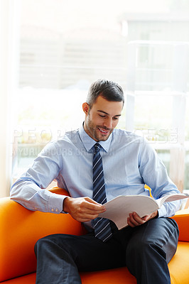 Buy stock photo Corporate, office and man reading magazine or catalog with waiting for appointment and work break with smile. Business, book and happy lawyer guy on sofa with law journal for information and learning