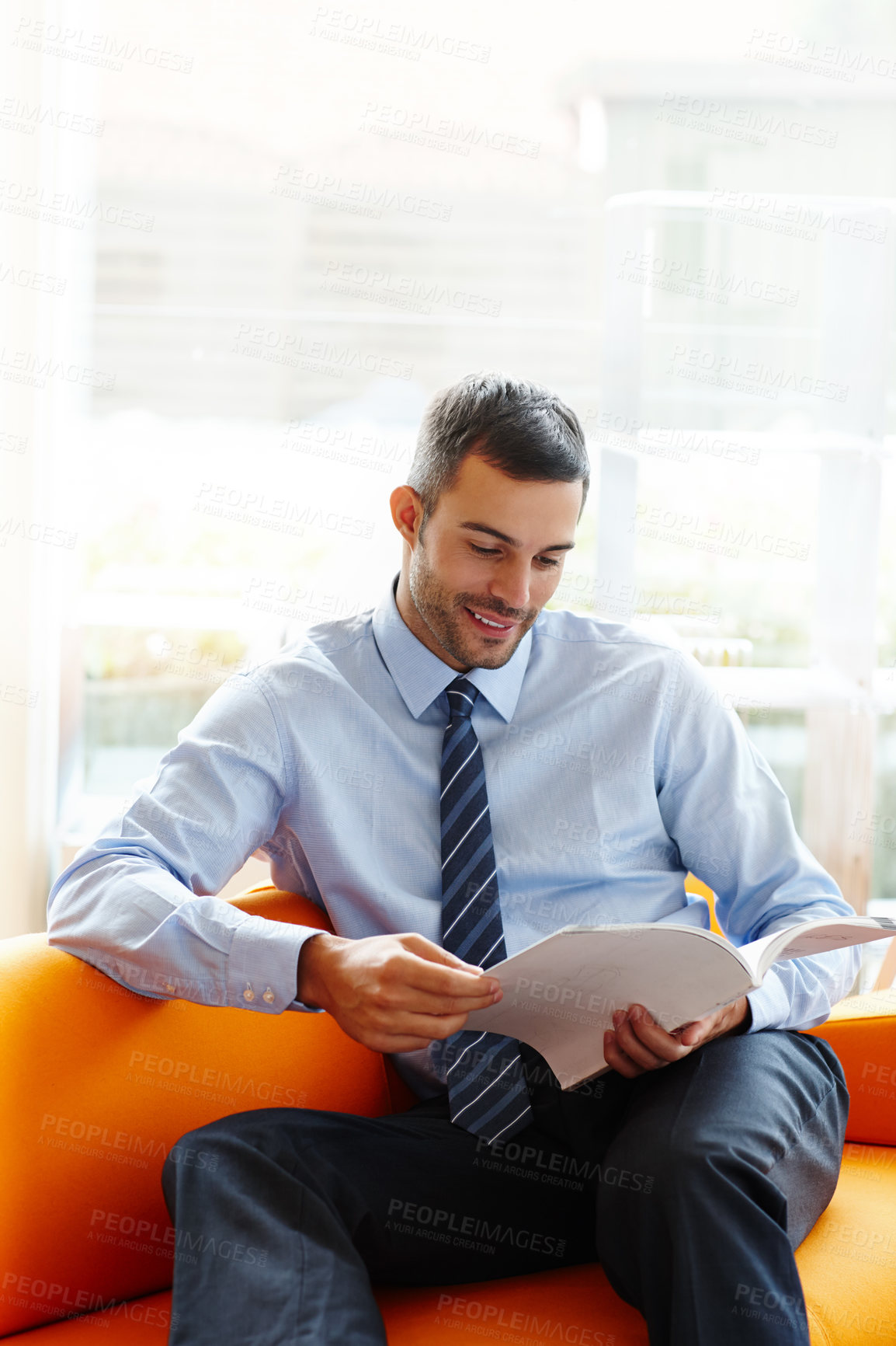 Buy stock photo Corporate, office and man reading magazine or catalog with waiting for appointment and work break with smile. Business, book and happy lawyer guy on sofa with law journal for information and learning