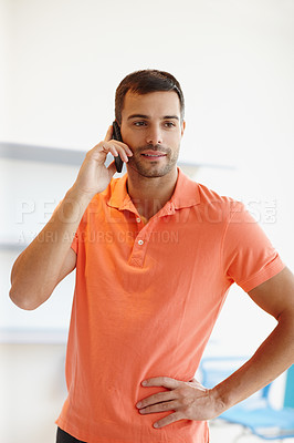 Buy stock photo A businessman on a phone call at work. A modern successful man speaks confidently on the phone to a client while networking and growing his startup business. A confident man standing in an office