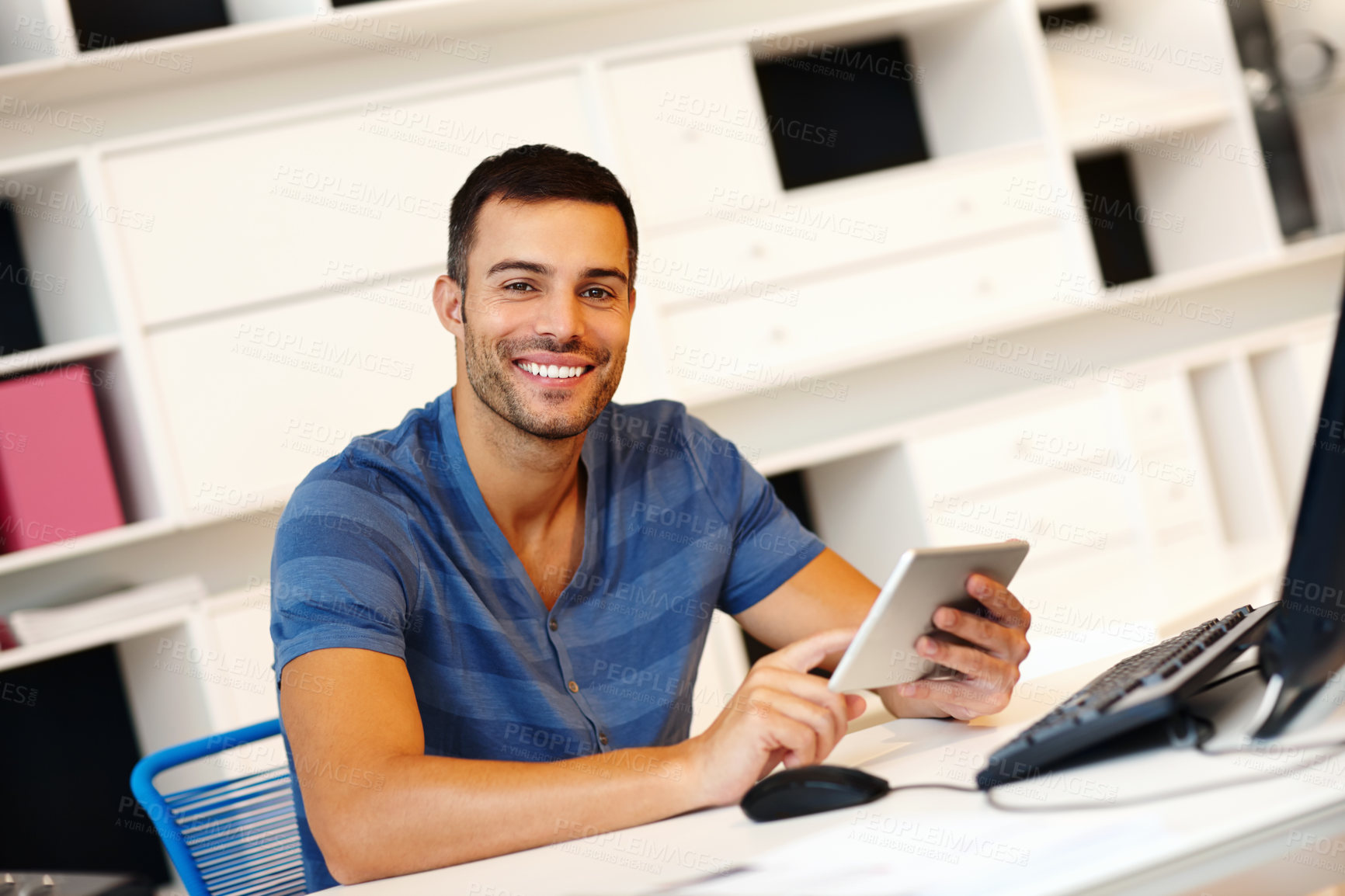 Buy stock photo A smiling young casually-dressed entrepreneur working on his digital tablet