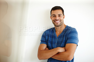 Buy stock photo Trendy, proud young man with his arms crossed leaning against a white wall. Portrait of confident, stylish handsome man with his arms folded. Relaxed posing against a studio background 



