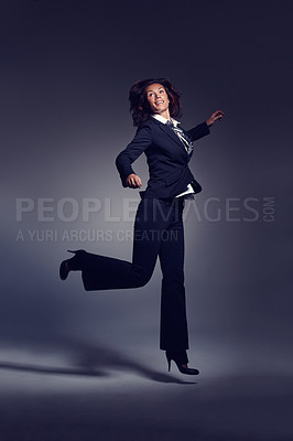 Buy stock photo Portrait of enthusiastic and ecstatic happy business woman in elegant suit jumping carefree in air, flying inspired by the success and celebrating goal achievement against a dark studio background
