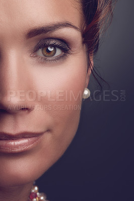 Buy stock photo Portrait of an elegant woman with makeup. Face of a beauty vintage style model wearing mascara and pearl earring. Closeup of lady with hazel eyes and flawless looking skin isolated on dark background