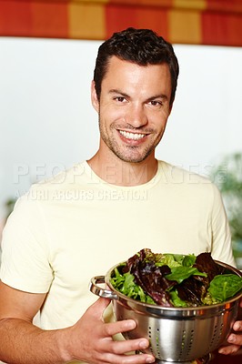 Buy stock photo A man standing in the kitchen holding a bowl of lettuce 
