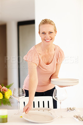 Buy stock photo A beautiful woman setting the table at home