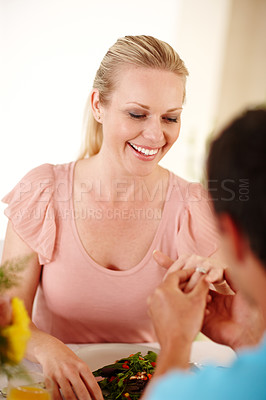 Buy stock photo A beautiful woman smiling as her fiancee slips a ring on her finger 